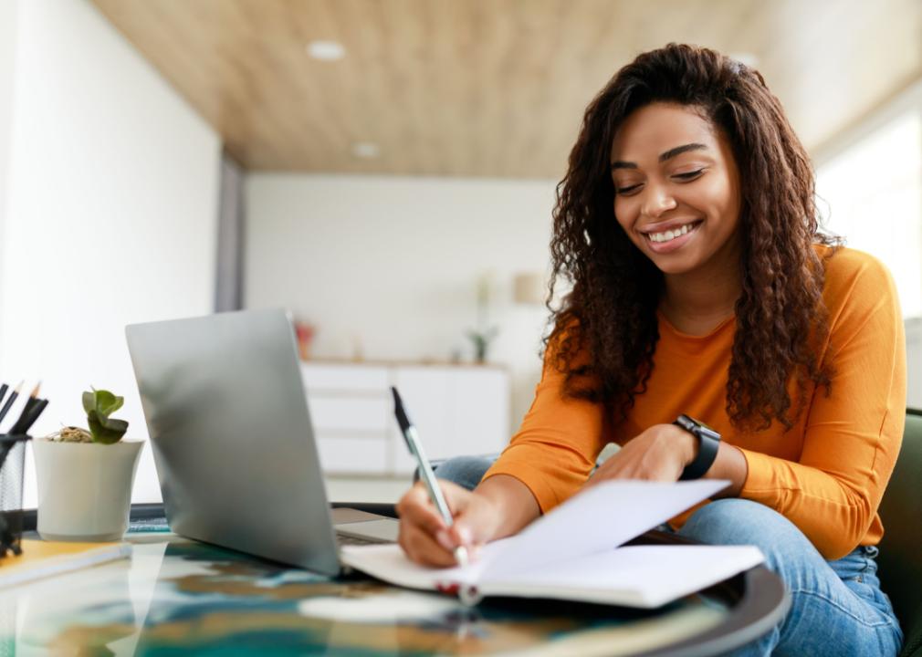 Smiling woman working at desk with laptop.