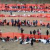 Migrants await processing by immigration authorities after crossing the US-Mexico border in Eagle Pass, Texas, December 20, 2023