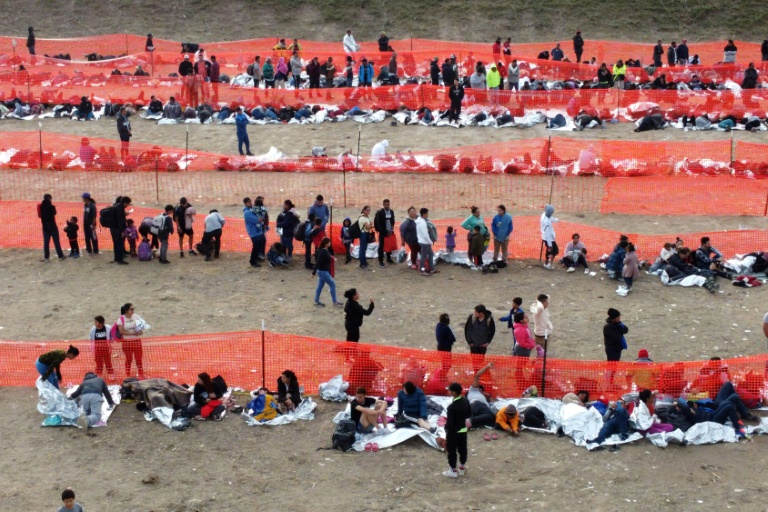 Migrants await processing by immigration authorities after crossing the US-Mexico border in Eagle Pass, Texas, December 20, 2023