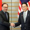 Japan's Prime Minister Fumio Kishida (R) shakes hands with Malaysia's Prime Minister Anwar Ibrahim at the start of their bilateral meeting in Tokyo