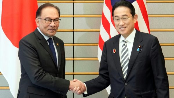 Japan's Prime Minister Fumio Kishida (R) shakes hands with Malaysia's Prime Minister Anwar Ibrahim at the start of their bilateral meeting in Tokyo