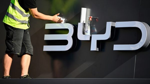 A worker cleans the company logo of Chinese carmaker BYD at their booth before the official launch of the International Motor Show (IAA) in the center of Munich, southern Germany, on September 4, 2023