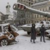 Kyiv residents walk past destroyed Russian military vehicles blanketed in snow in the centre of the Ukrainian capital