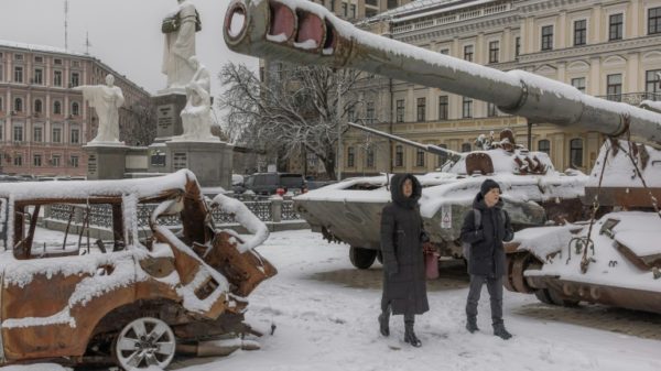 Kyiv residents walk past destroyed Russian military vehicles blanketed in snow in the centre of the Ukrainian capital