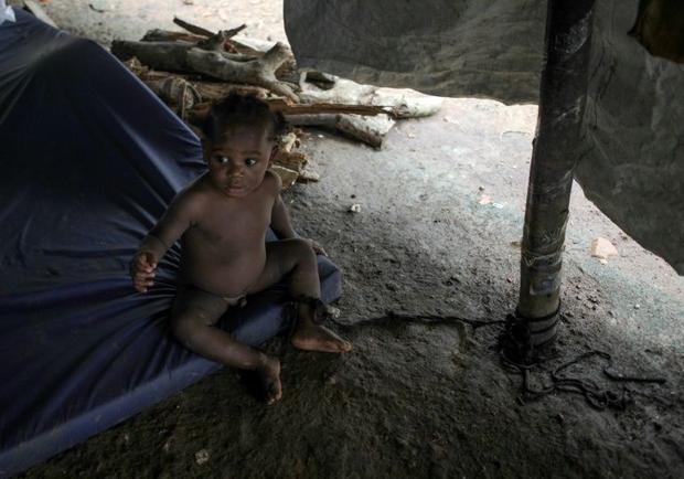 A baby is tied to a post to keep her from crawling away at the migrant camp in La Penita  Panama  wh...