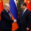 Russian Prime Minister Mikhail Mishustin (L) and Chinese President Xi Jinping shake hands before their meeting Wednesday in Beijing