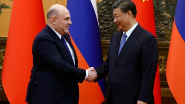 Russian Prime Minister Mikhail Mishustin (L) and Chinese President Xi Jinping shake hands before their meeting Wednesday in Beijing