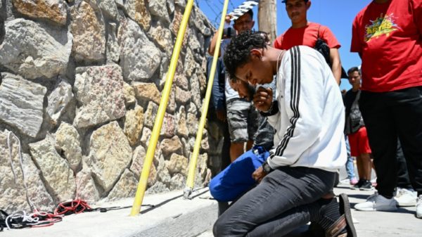 Jose Contreras, of Venezuela, knelt in prayer as migrants waited to turn themselves in for processing to US border agents in El Paso, Texas