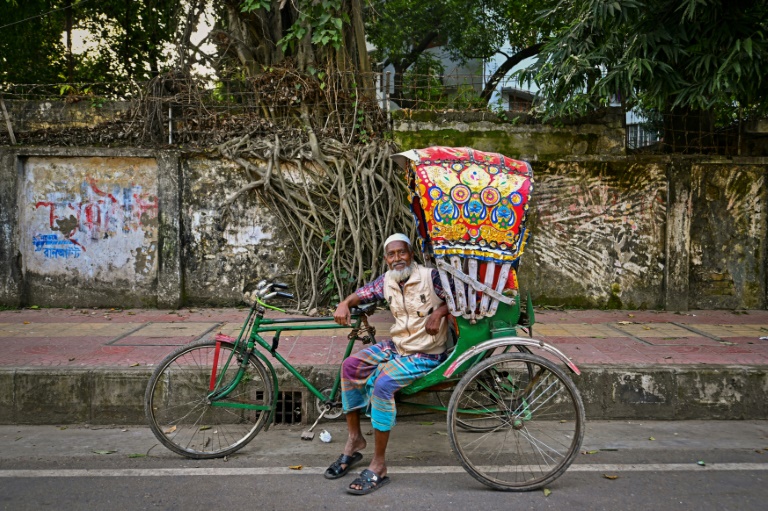 Bicycle rickshaw driver Mohammad Harun poses for a portrait with his vehicle on a street in Dhaka