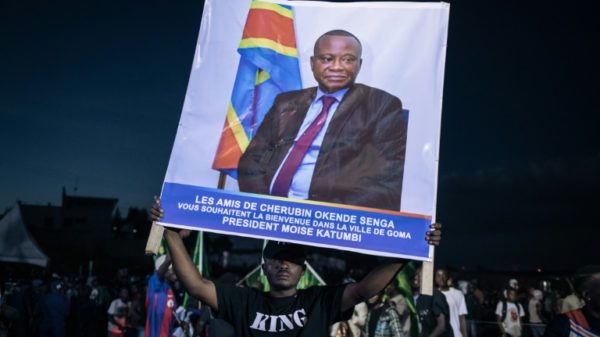 An opposition supporter at a rally in Goma last month with a poster of Cherubin Okende, who was gunned down in July