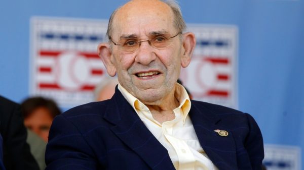 Nine people were charged with conspiracy in a sports memorabilia theft ring that took items from the museums of such legends as the late Yogi Berra, shown at a Baseball Hall of Fame ceremony in 2012