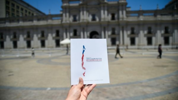 A man holds up a copy of Chile's proposed new Constitution in front of La Moneda Presidential Palace