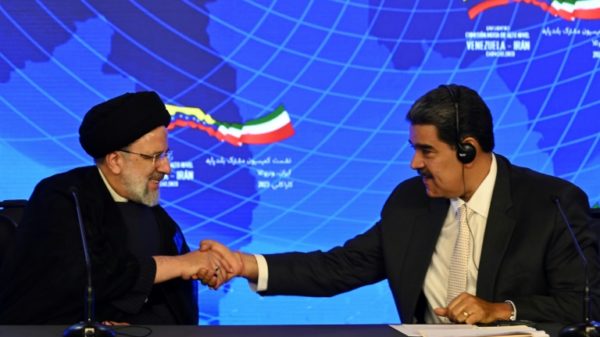 Iranian President Ebrahim Raisi (L) and Venezuelan President Nicolas Maduro shake hands during a joint press statement at Miraflores Presidential Palace in Caracas