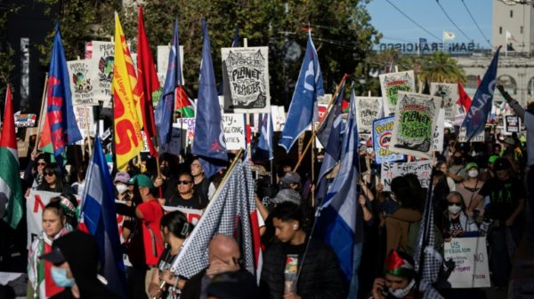 Demonstrators hold flags and placards during a 'No on APEC' protest on November 12, 2023 ahead of the summit in San Francisco