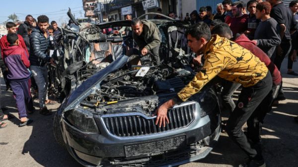 Crowds examine the car in which two journalists, Mustafa Thuria, a video stringer for AFP news agency, and Hamza Wael Dahdouh, a journalist with Al Jazeera television network, were killed in an air strike on Rafah blamed by Hamas on Israel