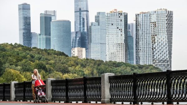 A woman pushes a pram in front Moscow's International Business Centre