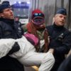 Police officers detain an environmental activist of the Code Red coalition during a demonstration against the aviation industry in Antwerp