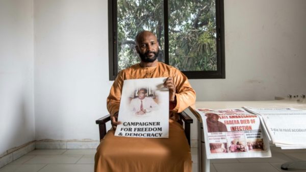 Baba Hydara holds a poster of his late father Deyda Hydara who was gunned down in 2004