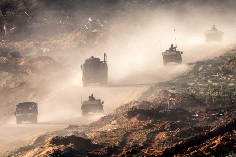 Israeli army vehicles move along a road in the Gaza Strip near a position along the border with southern Israel on Thursday