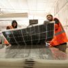 Workers push damaged solar panels into a machine to be recycled at the We Recycle Solar plant in Yuma, Arizona