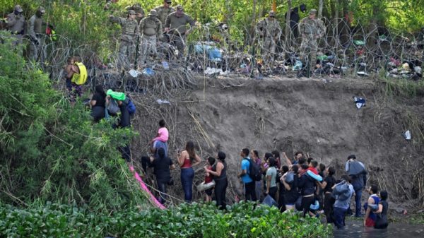 Migrants who crossed the Rio Bravo river (Rio Grande in the US) are stopped by members of the US National Guard reinforcing a barbed-wire fence along the US-Mexico border river in May 2023.