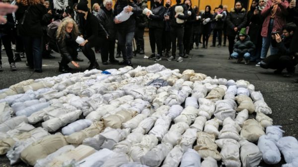 People gather and mourn in front of 500 baby dolls wrapped in a shroud, in remembrance of children killed in the Gaza Strip, in New York on December 28, 2023.